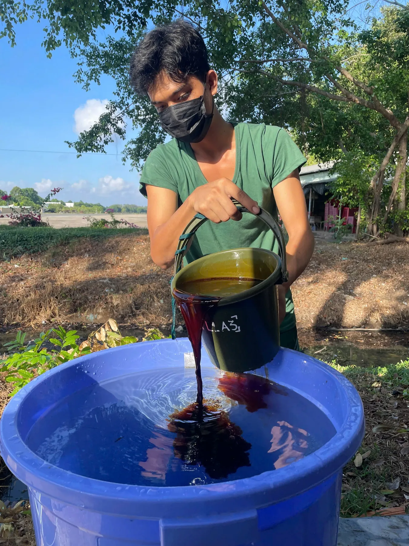 Field team handling a dark liquid sample during the Soc Trang pilot